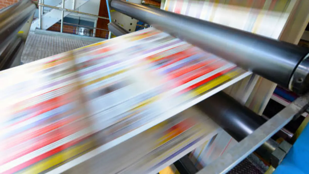Printed card sheets moving through the delivery rollers of an offset press