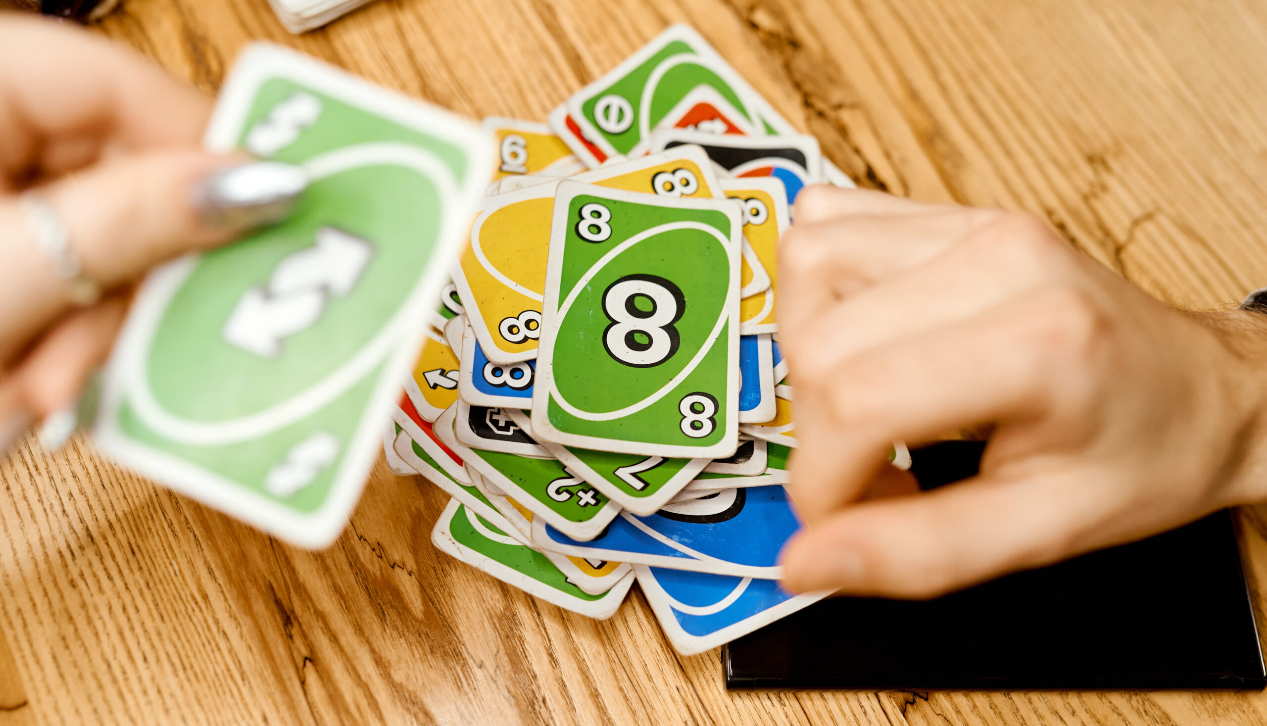 Hands shuffling colorful number playing cards over a wooden table