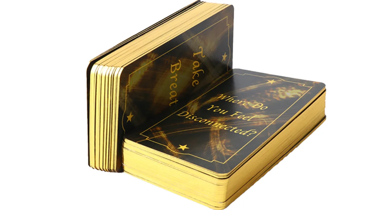 Two dark card decks with gilded gold edges stacked against a white background