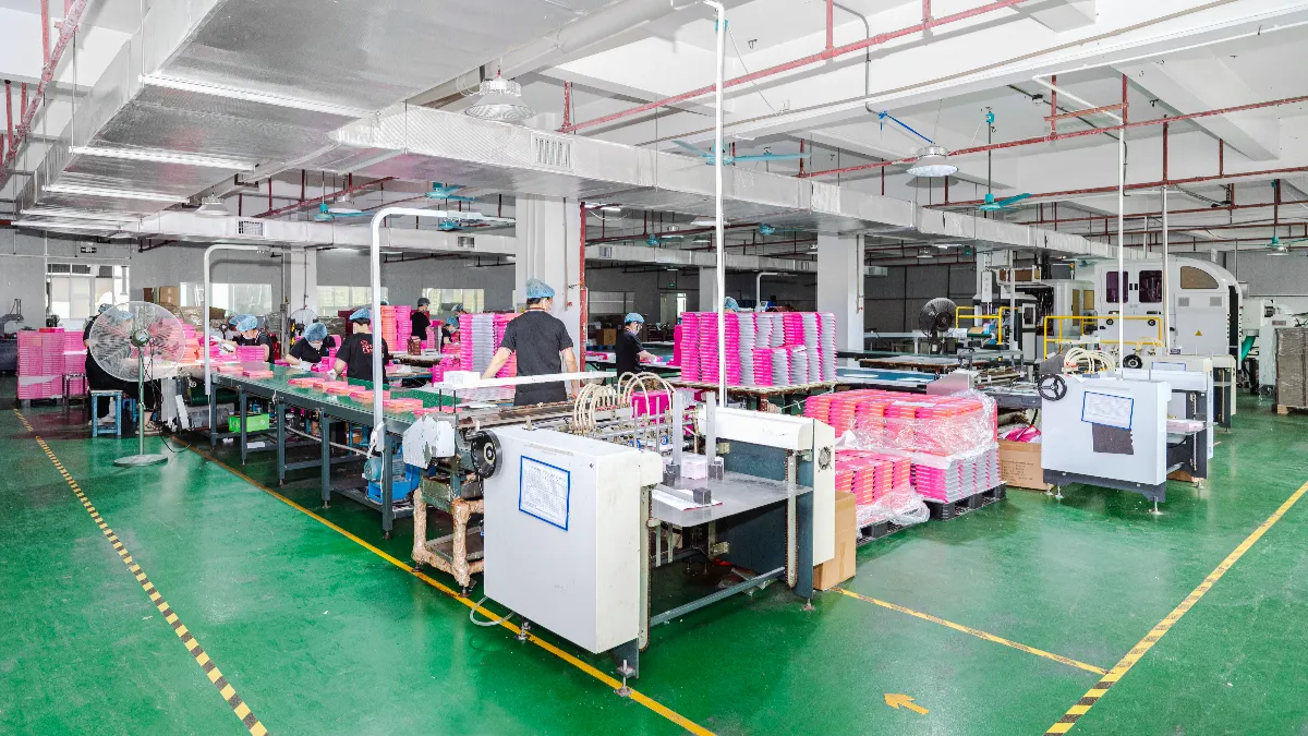 Wide view of a card printing factory floor with production lines, machines and stacks of pink printed cards