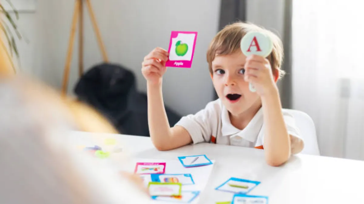 Child holding a picture flashcard and a letter card during a home learning session