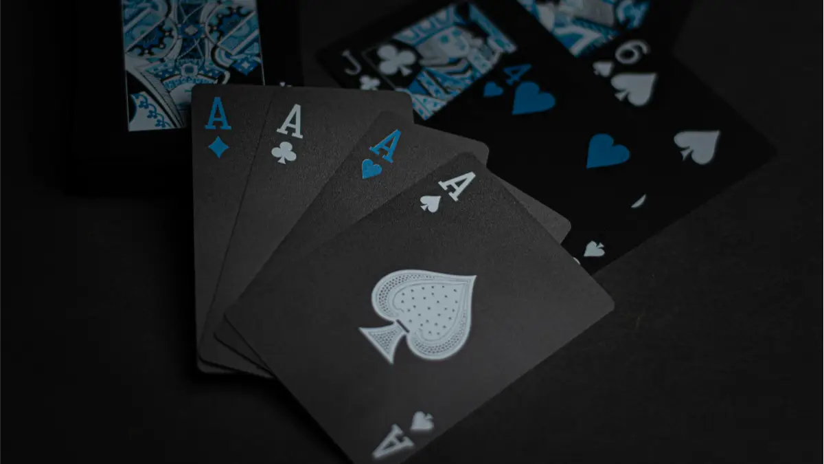 Black playing cards fanned across a dark surface, showing their matte printed faces and cut edges