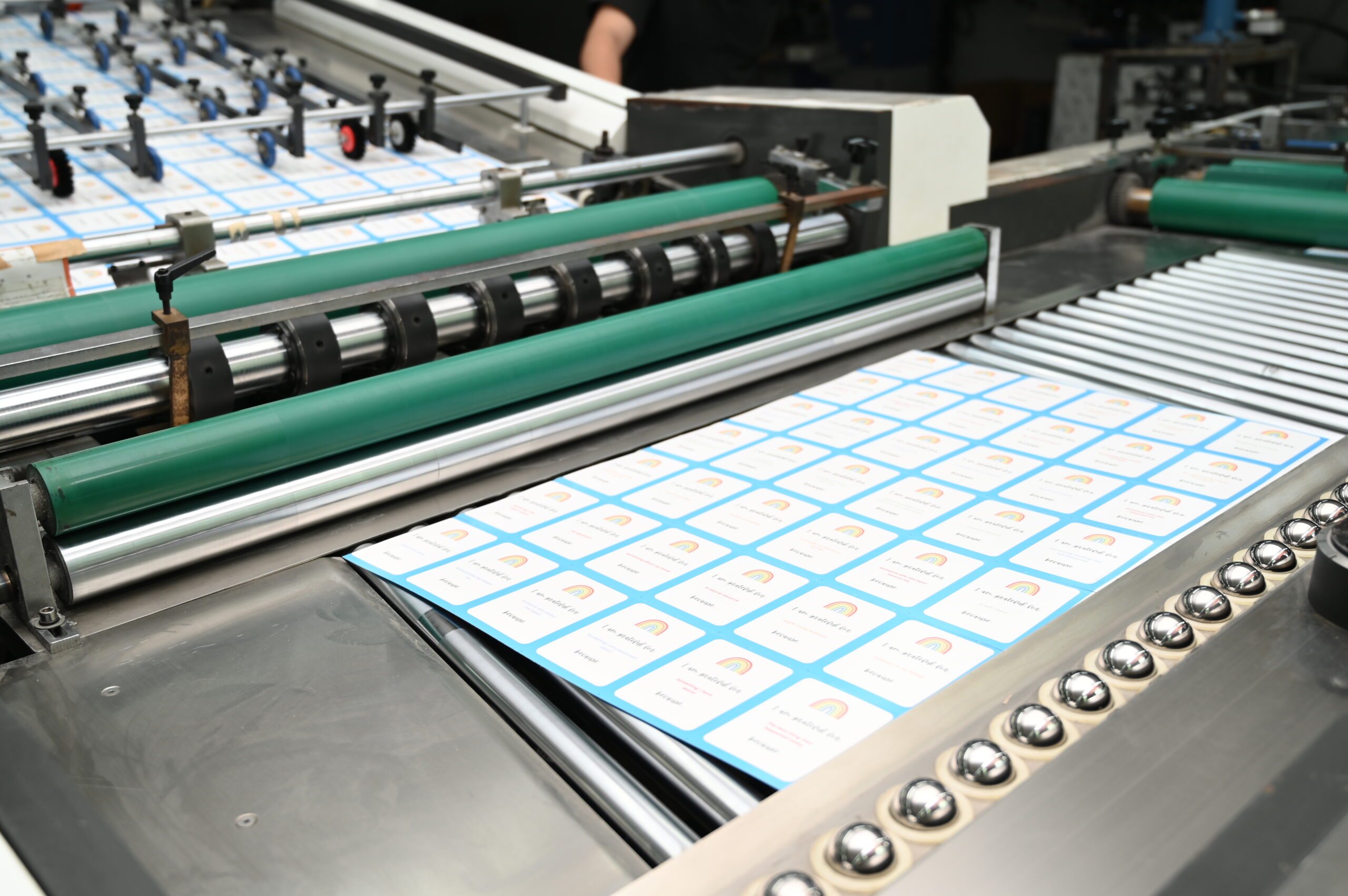 Offset printing press feeding printed card sheets through the roller line