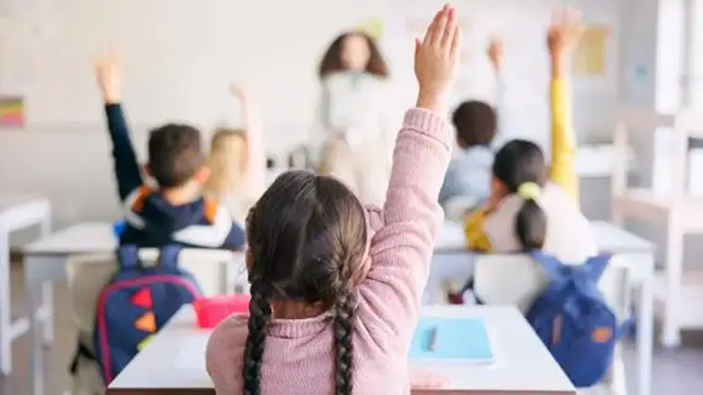 Education, raised hand and girl student in classroom with teacher for learning,